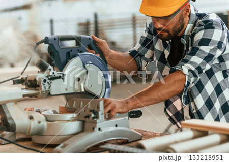Using the saw to cut the wood. Industrial worker in warehouse Using the saw to cut the wood. Industrial worker in warehouse 133218951