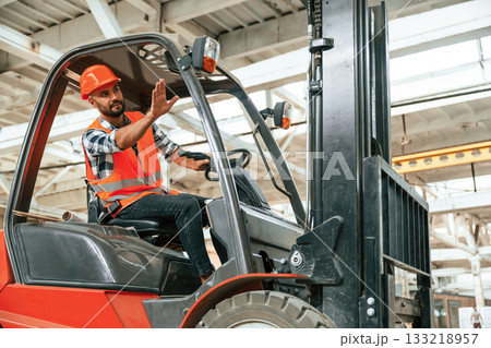 Driving the forklift. Industrial worker in wooden warehouse Driving the forklift. Industrial worker in wooden warehouse 133218957