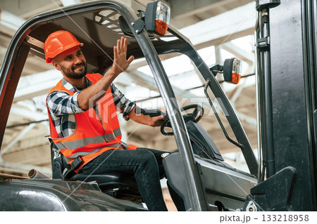 Driving the forklift. Industrial worker in wooden warehouse Driving the forklift. Industrial worker in wooden warehouse 133218958