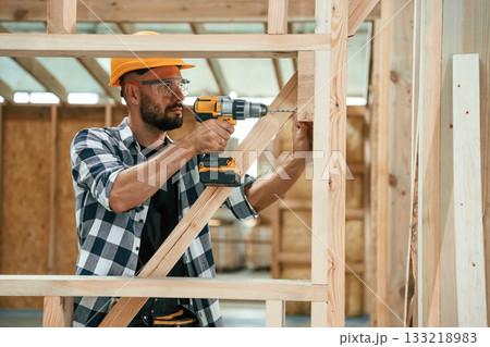 Drilling the hole in the wood. Industrial worker in warehouse, building the house 133218983