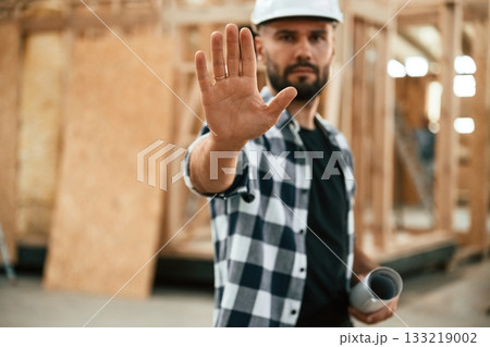 Stop hand gesture, no trespassing. Industrial worker in wooden warehouse 133219002