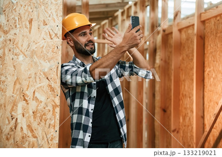 Using the smartphone. Industrial worker in wooden warehouse Using the smartphone. Industrial worker in wooden warehouse 133219021