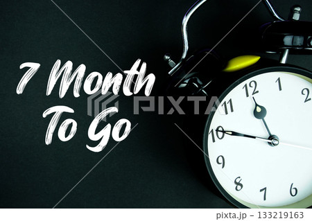 7 Month To Go text and alarm clock on black background 133219163