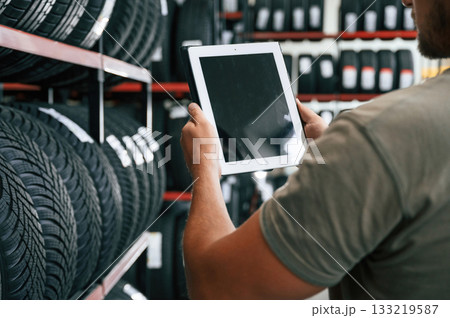 Copy space on the digital tablet. Man is in the tire fitting car service Copy space on the digital tablet. Man is in the tire fitting car service 133219587