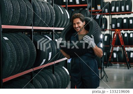 Positive facial expression. Man is in the tire fitting car service Positive facial expression. Man is in the tire fitting car service 133219606