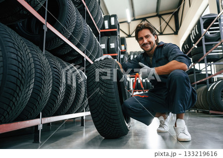 Positive facial expression. Man is in the tire fitting car service Positive facial expression. Man is in the tire fitting car service 133219616