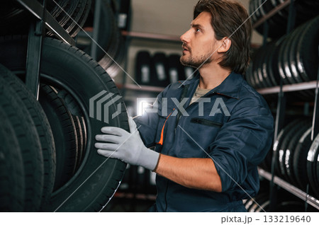 In the warehouse. Man is in the tire fitting car service In the warehouse. Man is in the tire fitting car service 133219640