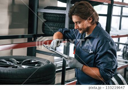 Writing the data into notepad. Man is in the tire fitting car service 133219647