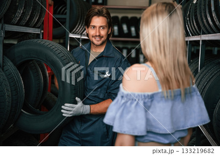 Giving the advice. Woman is in the tire fitting auto shop with worker 133219682