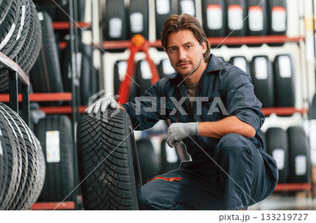 Front view, new wheel. Man is in the tire fitting car service 133219727