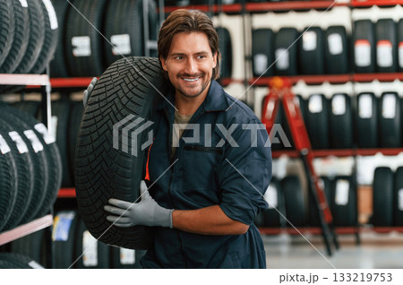 Cheerful, smiling. Man is in the tire fitting car service Cheerful, smiling. Man is in the tire fitting car service 133219753