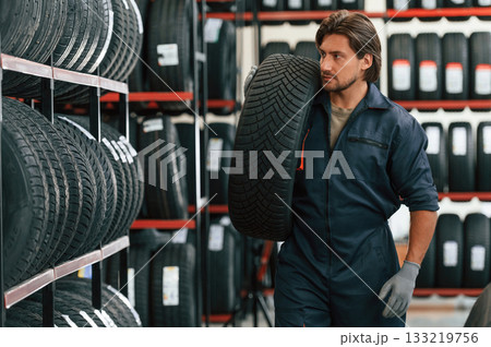 Moving the tire. Man is in the tire fitting car service Moving the tire. Man is in the tire fitting car service 133219756