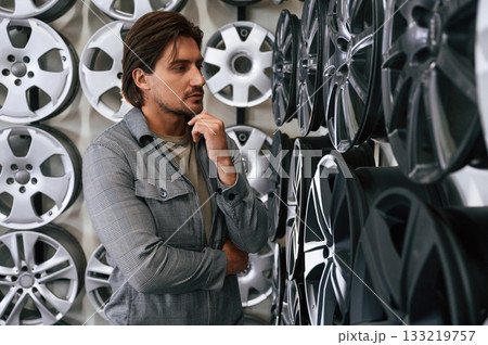 Thinking, choosing. Man is in the tire fitting car service 133219757