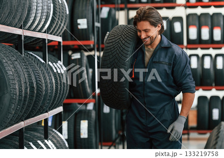 Cheerful, smiling. Man is in the tire fitting car service Cheerful, smiling. Man is in the tire fitting car service 133219758
