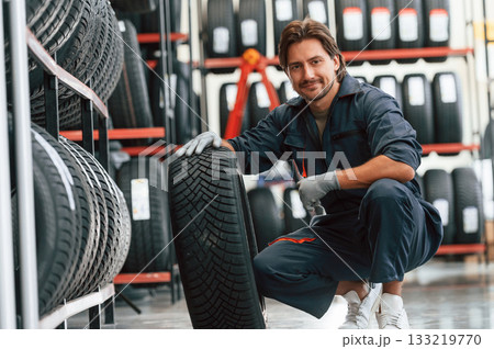 Sitting and showing the tire. Man is in the tire fitting car service Sitting and showing the tire. Man is in the tire fitting car service 133219770