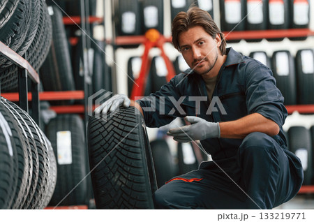 Sitting and showing the tire. Man is in the tire fitting car service Sitting and showing the tire. Man is in the tire fitting car service 133219771