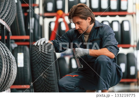 Sitting and showing the tire. Man is in the tire fitting car service Sitting and showing the tire. Man is in the tire fitting car service 133219775