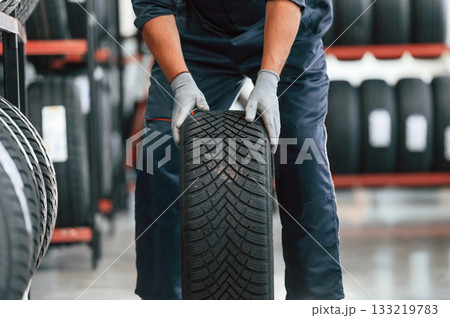 Detailed close up view, moving the wheel. Man is in the tire fitting car service 133219783