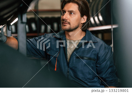 In professional uniform. Man is in the tire fitting car service In professional uniform. Man is in the tire fitting car service 133219801