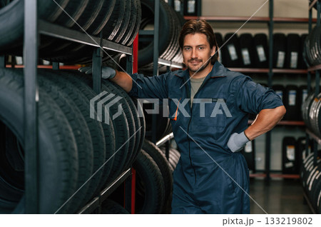 In professional uniform. Man is in the tire fitting car service In professional uniform. Man is in the tire fitting car service 133219802