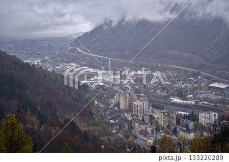 quiet town nestled among colorful mountains, majestic valley under overcast sky with peaceful river 133220289