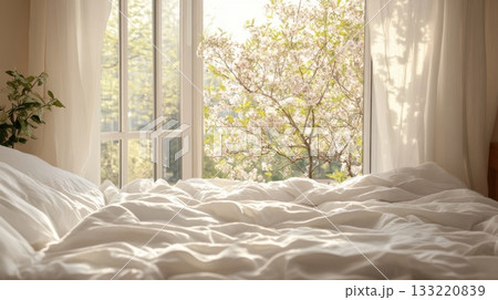Bright morning sunlight in soft white bedroom interior with blooming tree outside window 133220839