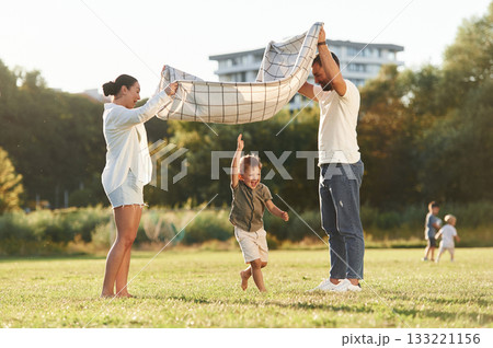 Mother and father are with son outdoors on the field 133221156