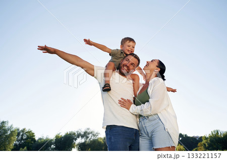 Hands to the sides, flying, imagination. Mother and father are with son outdoors on the field Hands to the sides, flying, imagination. Mother and father are with son outdoors on the field 133221157