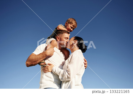 Bright blue sky, against it. Mother and father are with son outdoors on the field Bright blue sky, against it. Mother and father are with son outdoors on the field 133221165