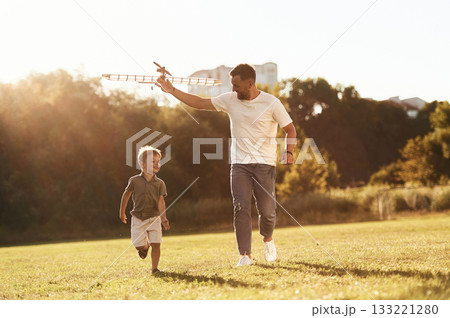 Running, fun. Father and son are on the field together with toy plane 133221280