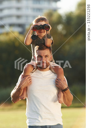 Looking through the binocular. Father and son are together on the field Looking through the binocular. Father and son are together on the field 133221298