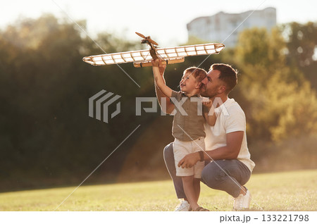 Happy facial expression, fun. Father and son are on the field together with toy plane 133221798
