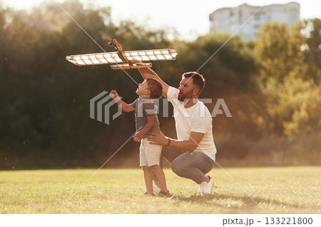 Happy facial expression, fun. Father and son are on the field together with toy plane Happy facial expression, fun. Father and son are on the field together with toy plane 133221800
