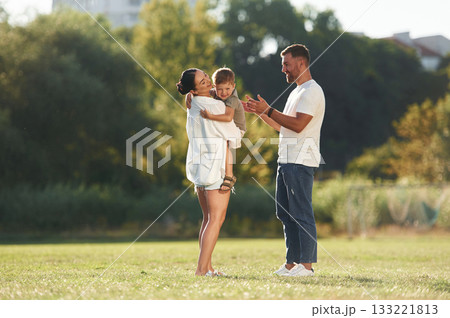 Family bonding. Mother and father are with son outdoors on the field Family bonding. Mother and father are with son outdoors on the field 133221813