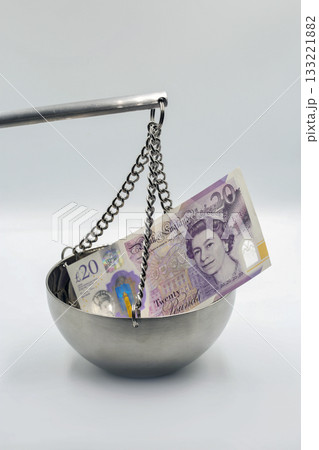 British 20 pound sterling banknote on metal balance scale closeup. British 20 pound sterling banknote on metal balance scale closeup. 133221882