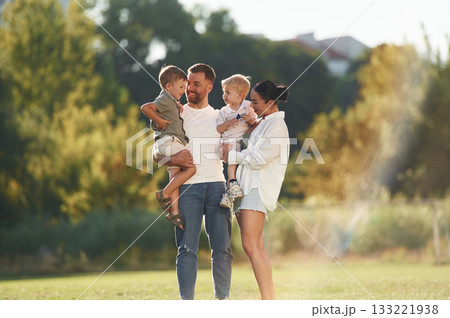 Standing together. Parents with two little sons are on the field 133221938