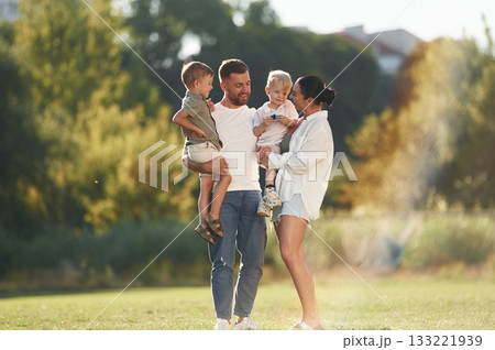 Standing together. Parents with two little sons are on the field 133221939