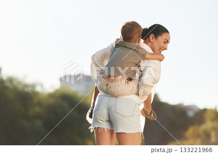 Holding kid on the shoulders. Woman with her little son are on the field together 133221966