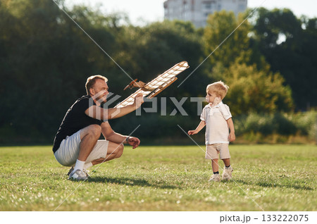 Father and son are on the field together with toy plane Father and son are on the field together with toy plane 133222075