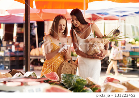 Holds a melon. Two women are together on the marker or bazaar 133222452