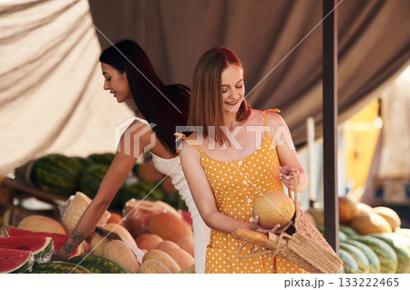 Holds a melon. Two women are together on the marker or bazaar 133222465