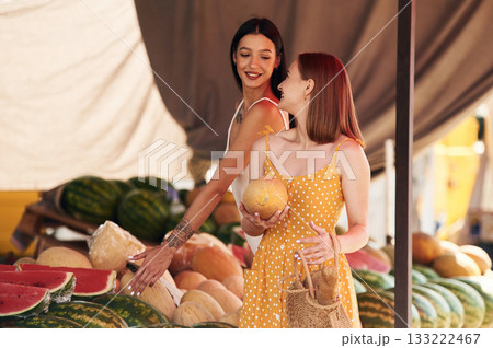 Friend is holding the melon. Two women are together on the marker or bazaar Friend is holding the melon. Two women are together on the marker or bazaar 133222467
