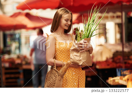 With spring onion. Young woman is on the vegetable market or bazaar 133222577