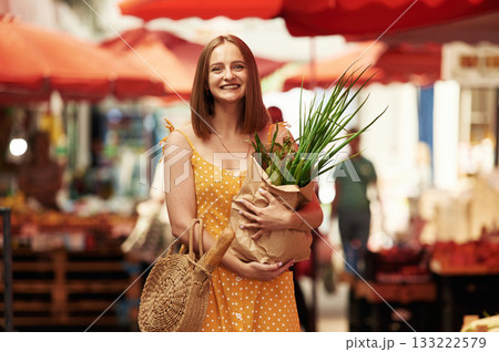 With spring onion. Young woman is on the vegetable market or bazaar With spring onion. Young woman is on the vegetable market or bazaar 133222579