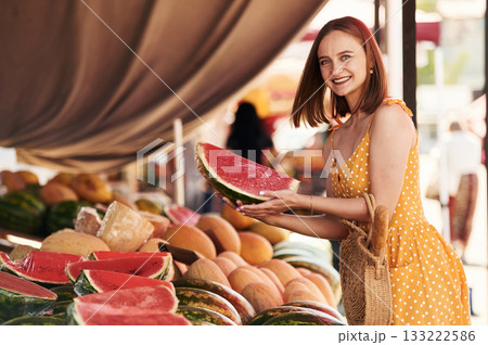 Yellow dress, and with watermelon. Young woman is on the vegetable market or bazaar 133222586