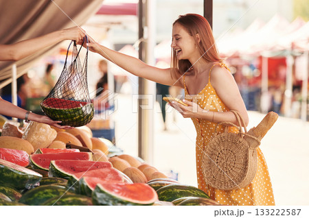Yellow dress, and with watermelon. Young woman is on the vegetable market or bazaar 133222587
