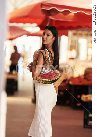 Standing and posing. Young woman is on the vegetable market or bazaar 133222625