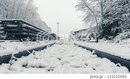 Quiet industrial zone blanketed in snow with distant factory outlines 133222685
