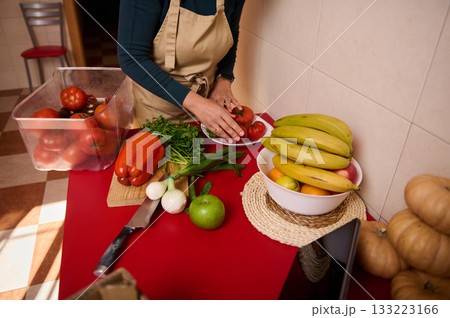 Home Cooking: Person Preparing Fresh Vegetables And Fruit On Red Counter Home Cooking: Person Preparing Fresh Vegetables And Fruit On Red Counter 133223166