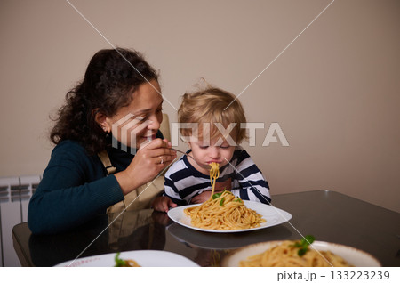 Mother And Child Share Spaghetti Dinner At Home, Warm Family Moment 133223239